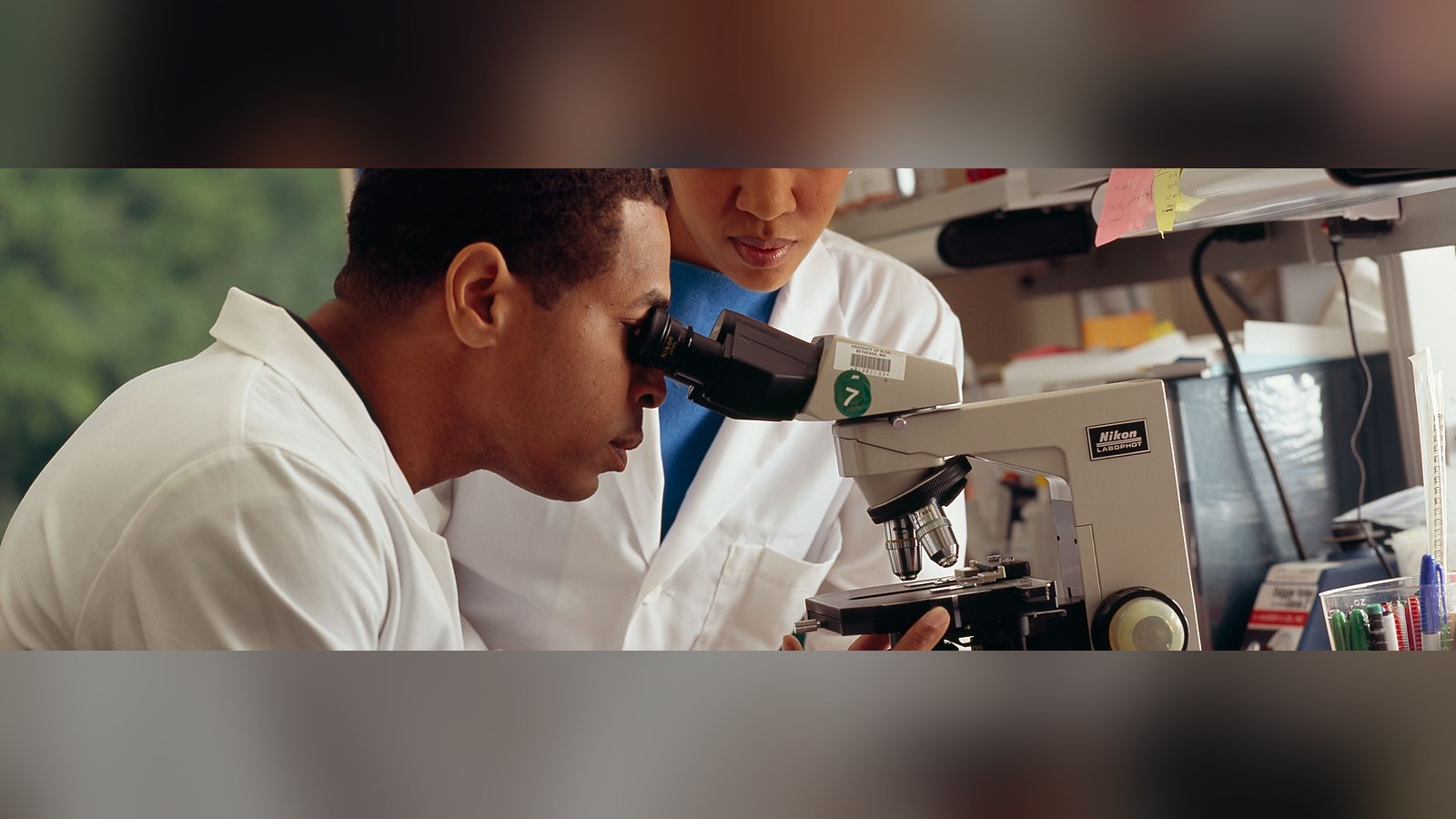Dos investigadores observando por un microscopio en un laboratorio
