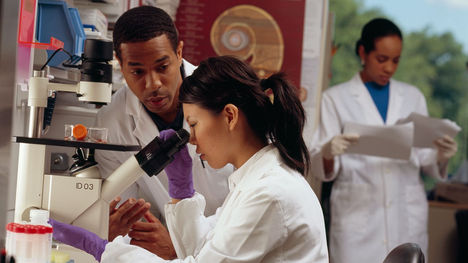 Investigadores trabajando con un microscopio en un laboratorio biomédico