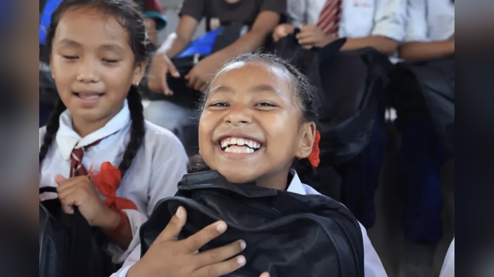 Dos alumnas sonrientes con sus mochilas al volver a clase en Nuwakot, Nepal, tras las inundaciones