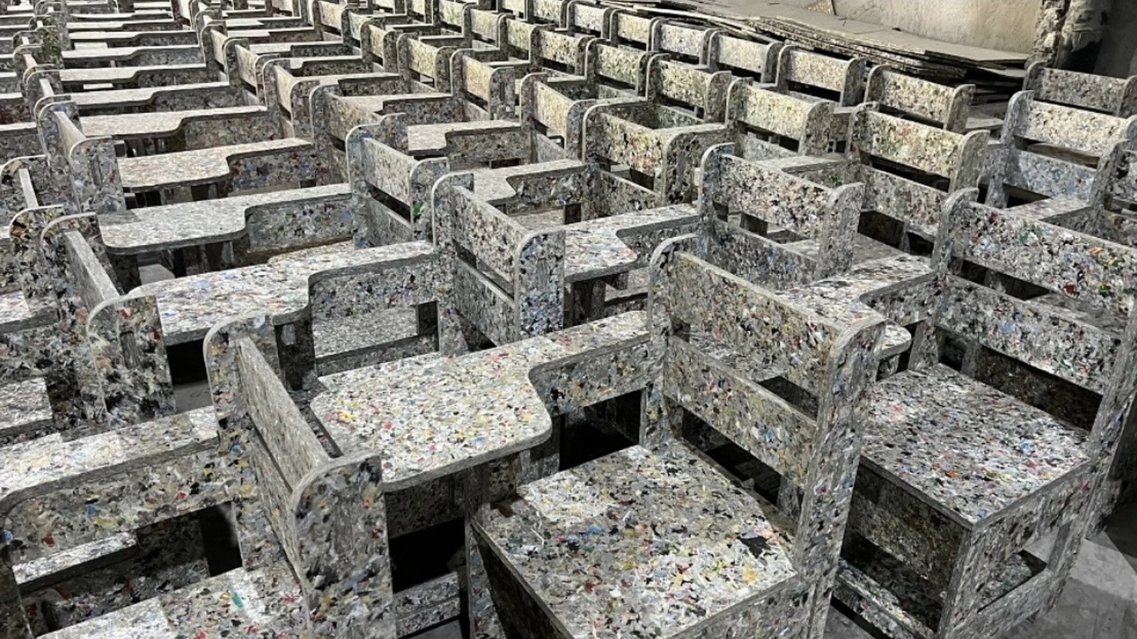 Filas de sillas escolares con pupitre fabricadas con plástico reciclado de colores