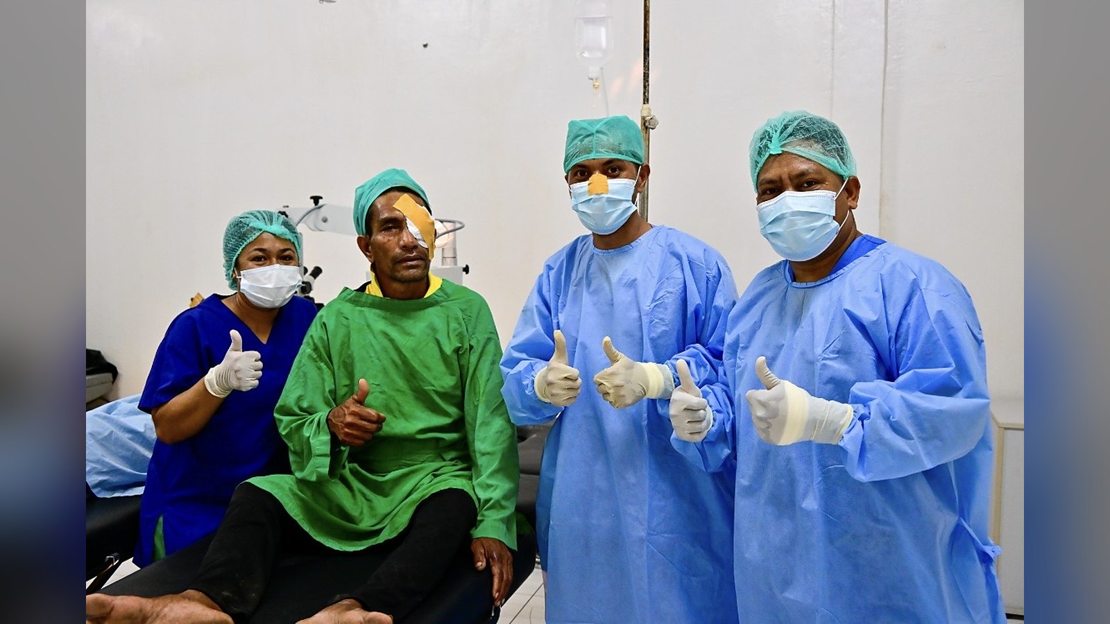 Tres sanitarios con el pulgar hacia arriba junto a un paciente con el ojo tapado tras una intervención en Timor-Leste